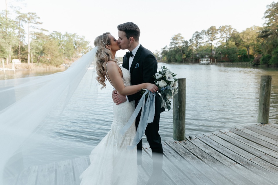 Taylor and John sharing a kiss on the waterfront dock