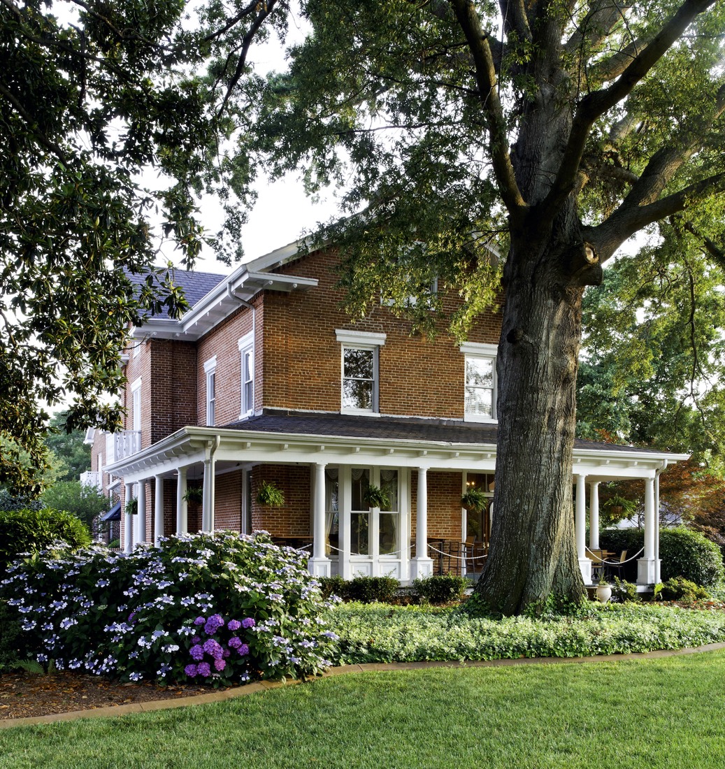 Flowering hydrangeas, garden borders, and an old oak beside the Manor's exterior porches