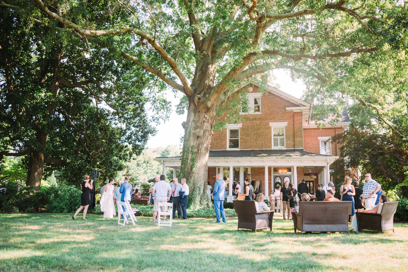 Wedding guests gathering beneath the old oak tree in front of Church Point Manor
