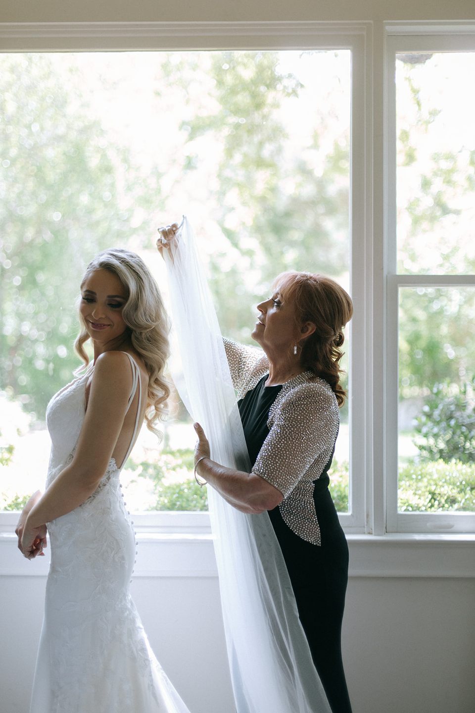 A bride getting dressed beside the sunlit windows in the Bridal Cottage