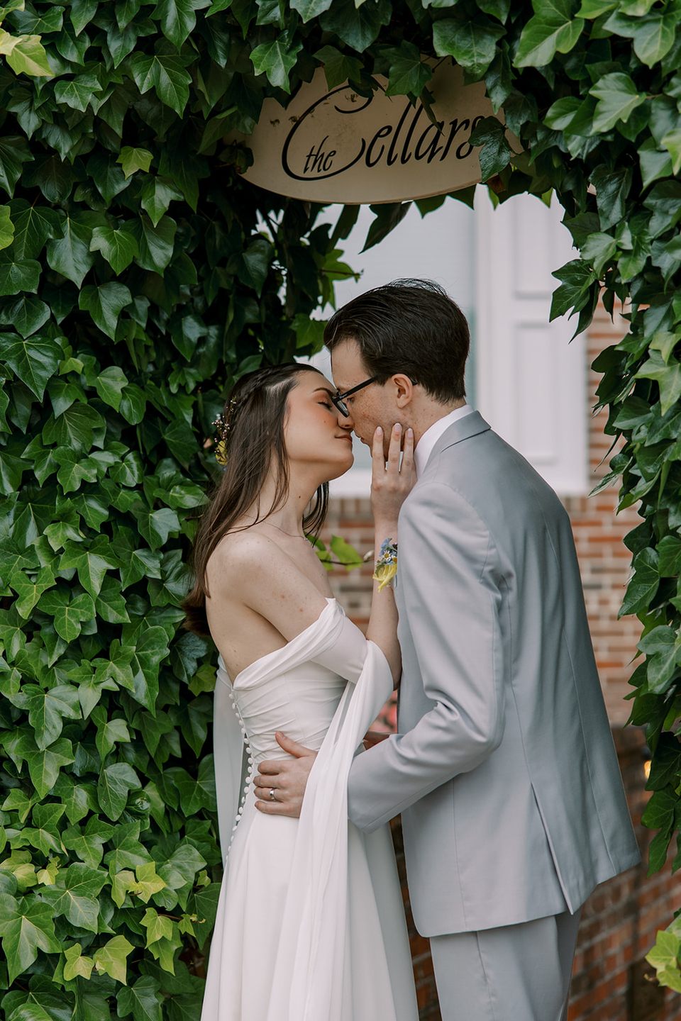 Newlyweds kissing beneath the ivy-framed entrance to the Cellars