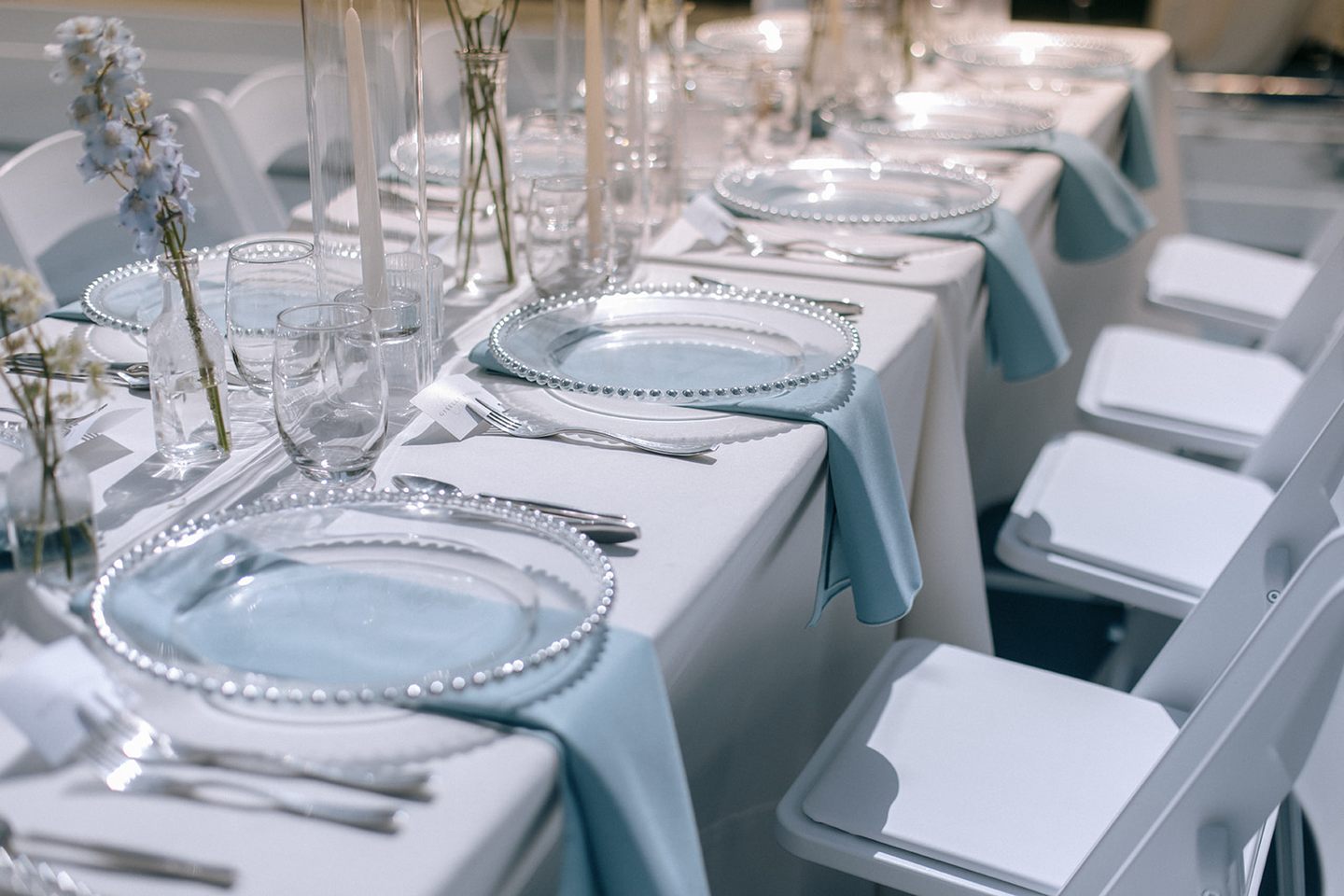 Wedding reception tables dressed with flowers, candles, plates, and glassware